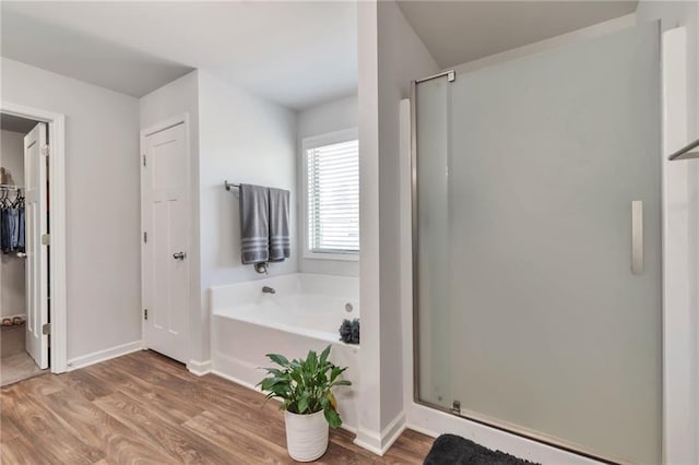 2021 Adam Acres Dr, Lawrenceville, GA 30043 - full bathroom featuring baseboards, a spacious closet, a shower stall, a bath, and wood finished floors