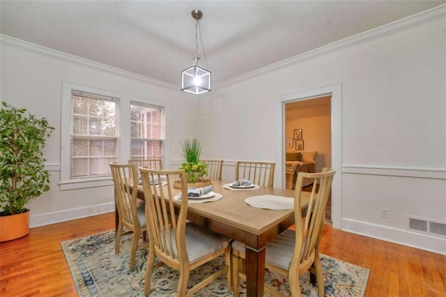 dining room with light wood-type flooring and crown molding