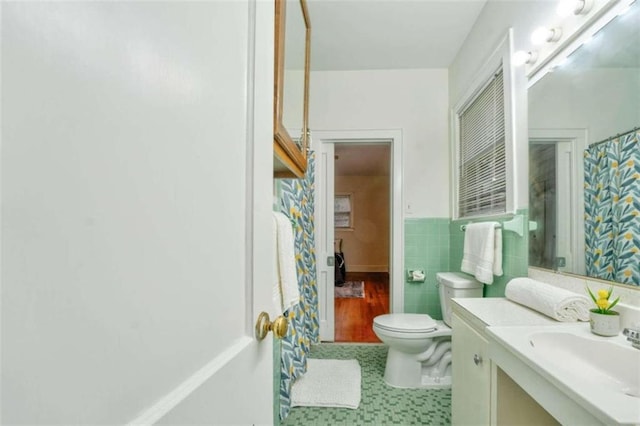 bathroom with vanity, toilet, and tile walls