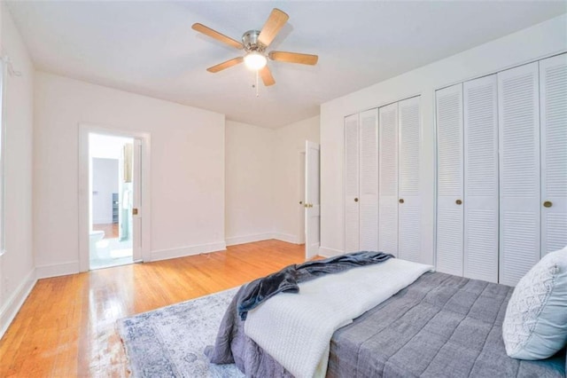 bedroom with hardwood / wood-style floors, ceiling fan, and two closets