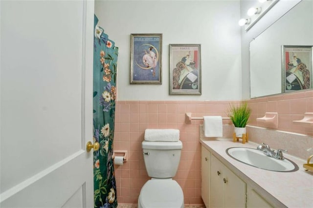 bathroom with vanity, toilet, and tile walls