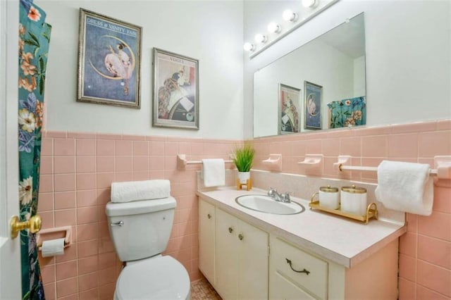 bathroom with vanity, toilet, and tile walls