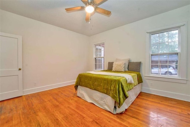 bedroom featuring hardwood / wood-style floors, ceiling fan, and multiple windows