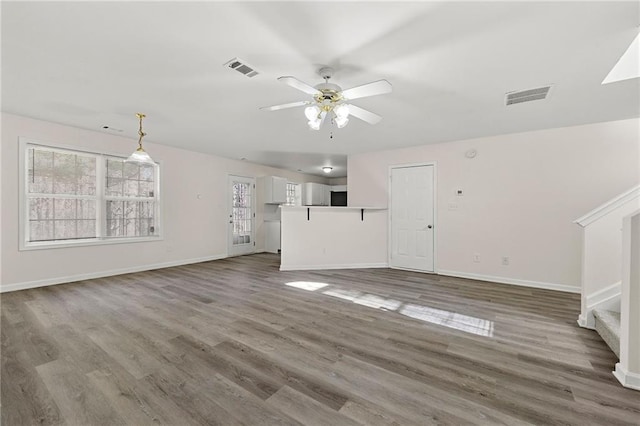 unfurnished living room featuring wood finished floors, visible vents, and a ceiling fan