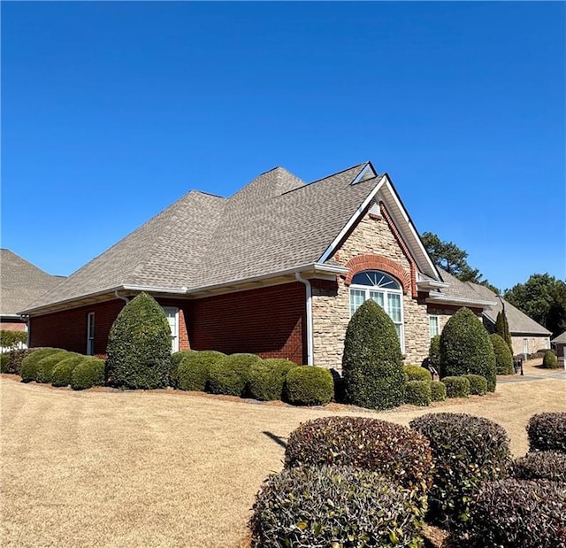 view of front of home with stone siding, brick siding, and roof with shingles