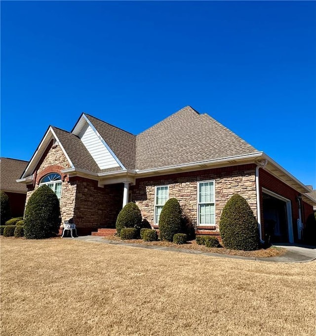 view of front facade featuring a garage, stone siding, a shingled roof, and a front lawn