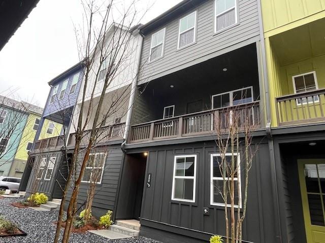 back of house featuring board and batten siding, entry steps, and a balcony