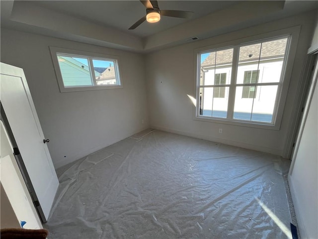 unfurnished room featuring visible vents, baseboards, a raised ceiling, and a ceiling fan