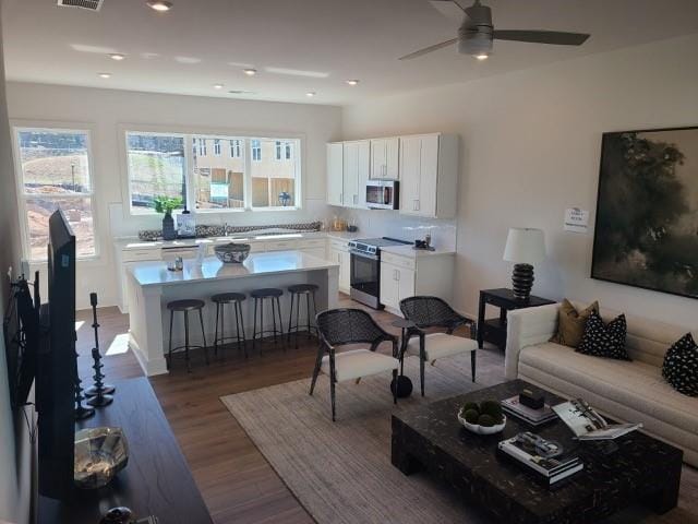 living area with a ceiling fan, visible vents, wood finished floors, and recessed lighting