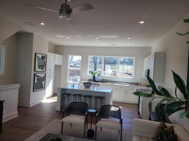 kitchen featuring wood finished floors, a center island, white cabinetry, and a healthy amount of sunlight