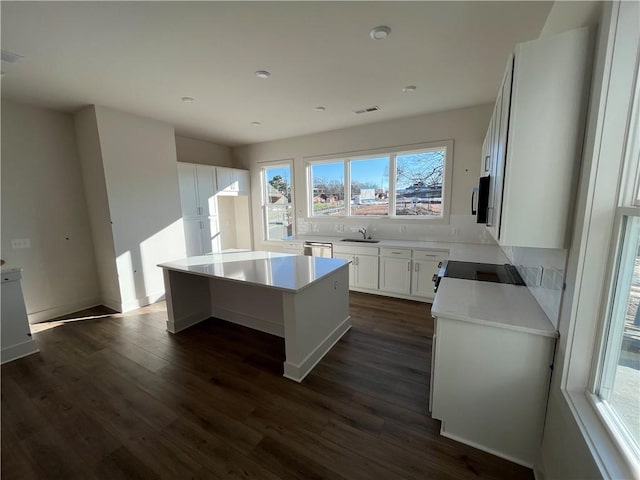 kitchen with white cabinetry, a center island, sink, plenty of natural light, and stove