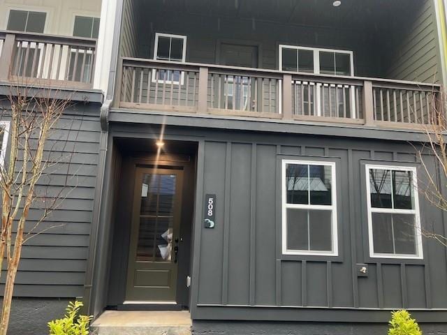 property entrance with board and batten siding and a balcony