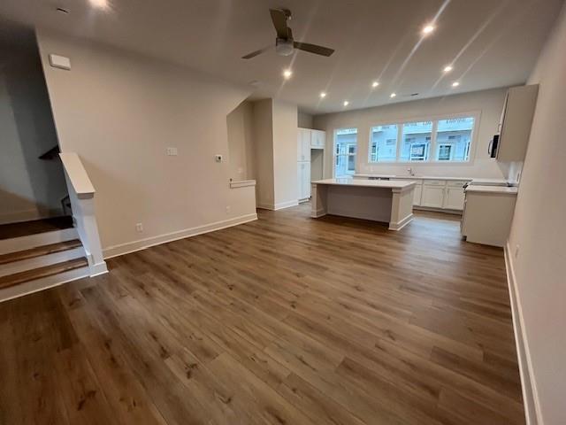 unfurnished living room featuring ceiling fan and dark hardwood / wood-style floors