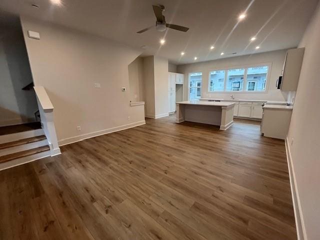 kitchen featuring a center island, dark wood-style flooring, white cabinetry, ceiling fan, and baseboards