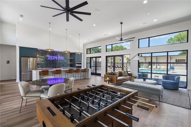 kitchen featuring ceiling fan, a towering ceiling, stainless steel refrigerator, and light hardwood / wood-style flooring