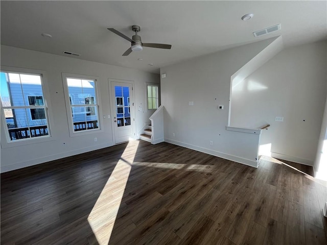 unfurnished living room with stairs, dark wood-style flooring, visible vents, and baseboards