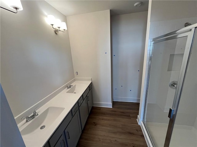 full bathroom with baseboards, wood finished floors, a sink, and a shower stall