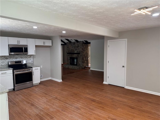 1516 Chase Ct, Riverdale, GA 30296 - kitchen featuring stainless steel appliances, a textured ceiling, white cabinets, light wood finished floors, and beam ceiling