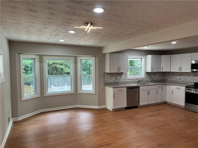 1516 Chase Ct, Riverdale, GA 30296 - kitchen with stainless steel appliances, decorative backsplash, wood finished floors, white cabinetry, and recessed lighting