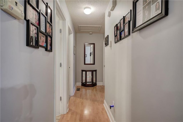 corridor with a textured ceiling and light wood-type flooring