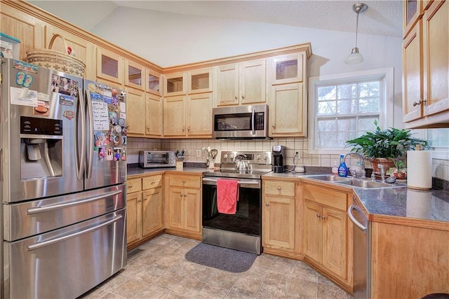 kitchen featuring lofted ceiling, sink, hanging light fixtures, stainless steel appliances, and decorative backsplash