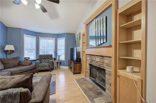 living room featuring a fireplace, light hardwood / wood-style flooring, built in features, and ceiling fan