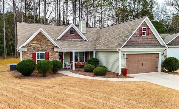 craftsman house with a garage, a chimney, concrete driveway, and a front lawn