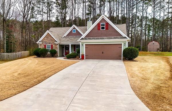 craftsman-style home with fence, concrete driveway, a front yard, a chimney, and an attached garage