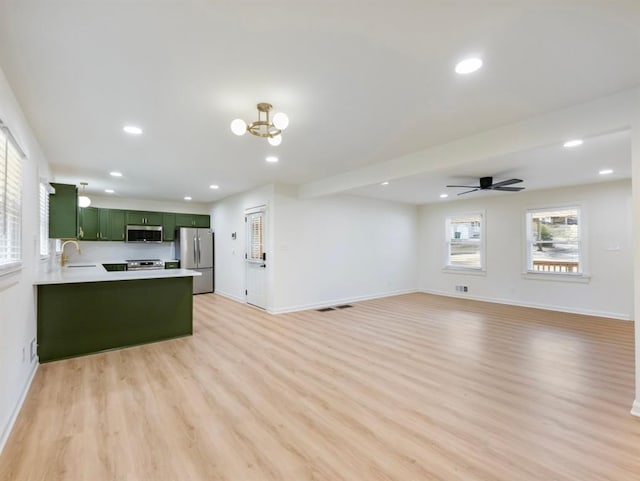 kitchen featuring sink, light hardwood / wood-style flooring, stainless steel appliances, green cabinetry, and kitchen peninsula