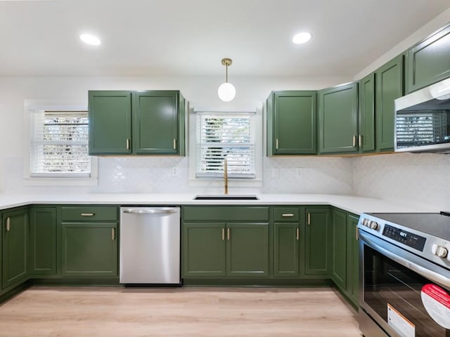 kitchen featuring sink, green cabinets, decorative light fixtures, and appliances with stainless steel finishes