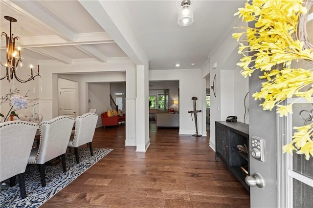 entryway featuring dark wood-type flooring, beam ceiling, a notable chandelier, and ornamental molding