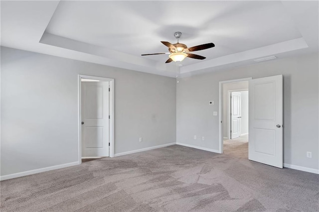 unfurnished bedroom with visible vents, a raised ceiling, light colored carpet, and baseboards