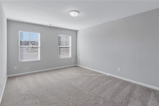 spare room with baseboards, visible vents, and light colored carpet