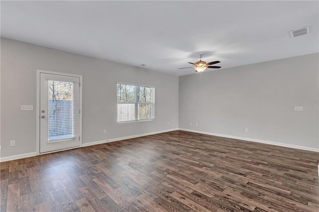 spare room featuring dark wood-type flooring, a healthy amount of sunlight, visible vents, and baseboards