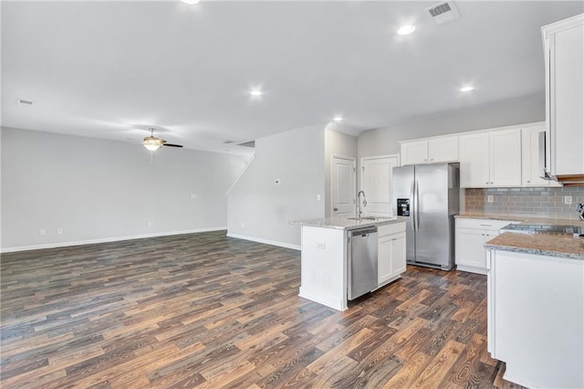 kitchen featuring an island with sink, ceiling fan, appliances with stainless steel finishes, light stone countertops, and white cabinetry