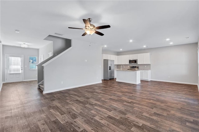 unfurnished living room featuring stairway, dark wood finished floors, visible vents, and baseboards