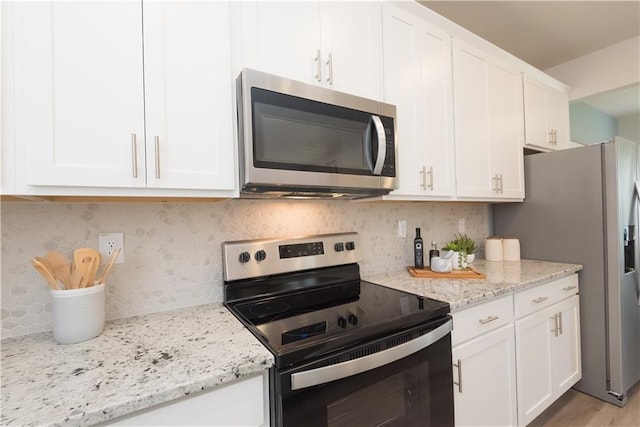 kitchen with white cabinetry, appliances with stainless steel finishes, light stone counters, and backsplash