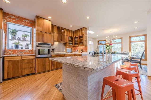 kitchen featuring decorative light fixtures, stainless steel appliances, an inviting chandelier, sink, and a center island with sink