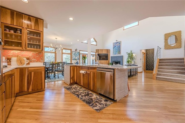 kitchen featuring light hardwood / wood-style floors, an island with sink, decorative backsplash, a kitchen breakfast bar, and stainless steel dishwasher