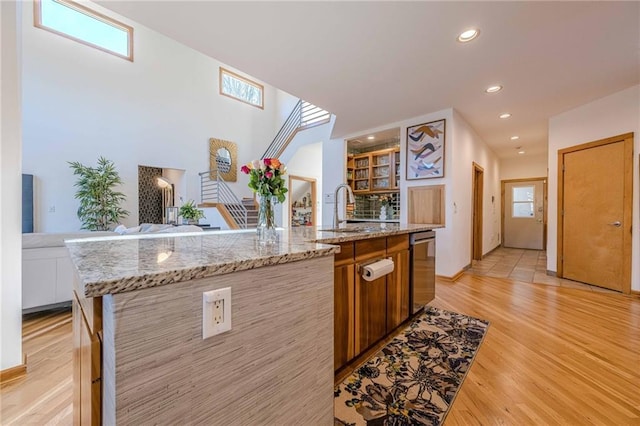 kitchen featuring an island with sink, plenty of natural light, dishwasher, light hardwood / wood-style flooring, and sink