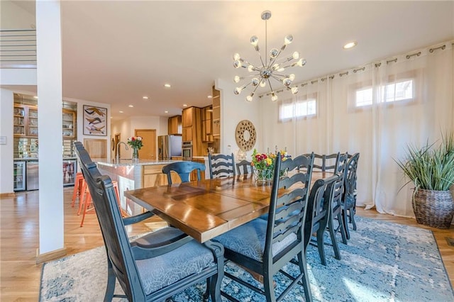 dining area with an inviting chandelier, wine cooler, and light hardwood / wood-style flooring