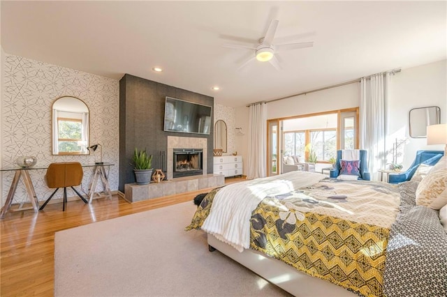 bedroom featuring ceiling fan, wood-type flooring, and a tile fireplace