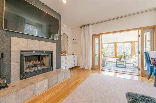 living room featuring a tile fireplace and light hardwood / wood-style flooring