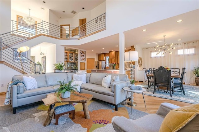 living room with a notable chandelier, a towering ceiling, and light hardwood / wood-style floors