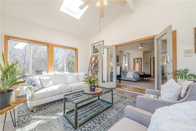 living room with ceiling fan, high vaulted ceiling, a skylight, and french doors