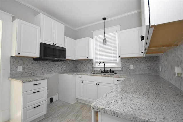 kitchen featuring pendant lighting, ornamental molding, sink, and white cabinets