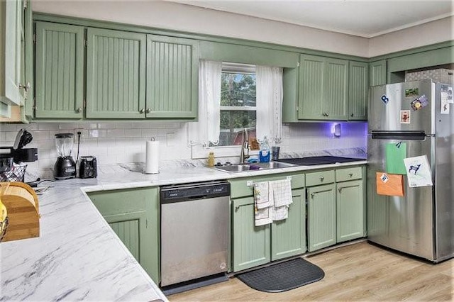 kitchen featuring tasteful backsplash, sink, green cabinetry, stainless steel appliances, and light wood-type flooring