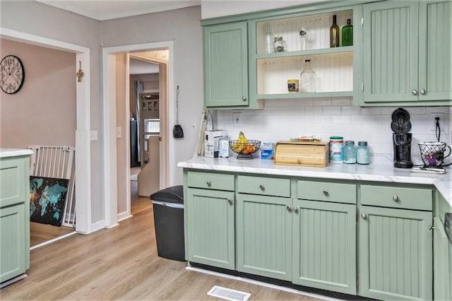 kitchen featuring green cabinets, backsplash, and light wood-type flooring