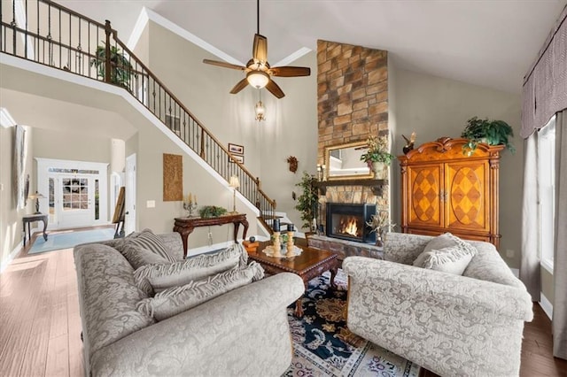 living room with stairs, a fireplace, high vaulted ceiling, and wood finished floors