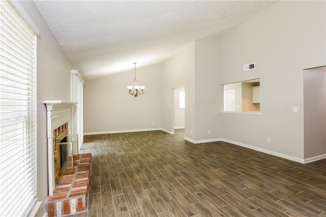 unfurnished living room with a brick fireplace, a textured ceiling, lofted ceiling, and a chandelier